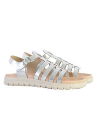 Sandalias metálicas plateadas con múltiples correas horizontales, hebilla ajustable en el tobillo, suela beige acolchada y parte inferior de goma blanca texturizada.