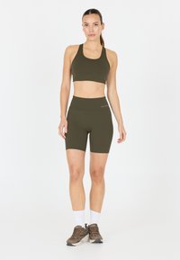 Olijfgroene sportbeha en set van hoog-getailleerde short, gemaakt van rekbaar materiaal met een soepele textuur. Heeft een effen kleurontwerp.