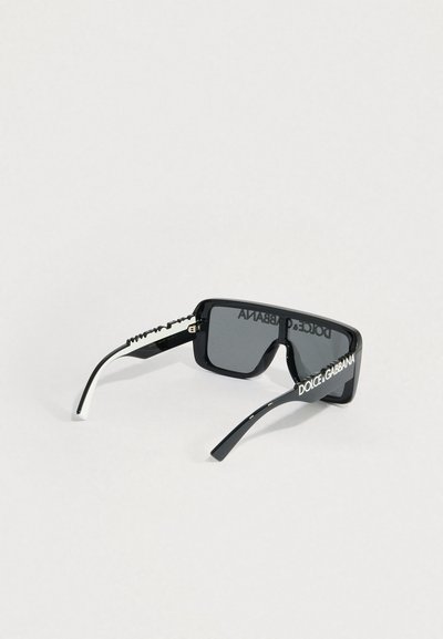 Mustad ristkülikukujulised päikeseprillid hallide läätsedega, millel on tekstureeritud valge aksent prillide varraste juures ja julge valge bränding raamidel.