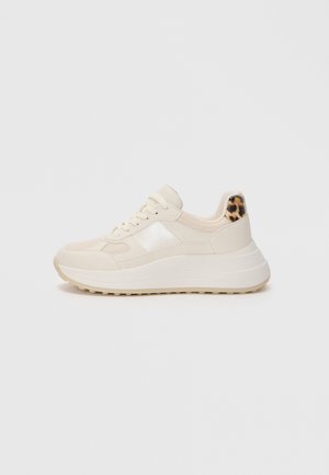 Basket plateforme beige avec un devant à lacets et un détail imprimé léopard au talon, présentée sur un fond clair.
