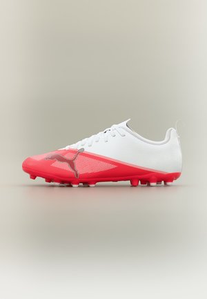 Άσπρο και κόκκινο ποδοσφαιρικό παπούτσι Puma με κορδόνια και διαμορφωμένες αγκράφες, εμφανίζεται από το πλάι σε ουδέτερο φόντο.