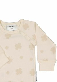 Ljusbeige långärmad babydress med subtila klöversmönster, med tryckknappar vid axeln och en mjuk tygkänsla.