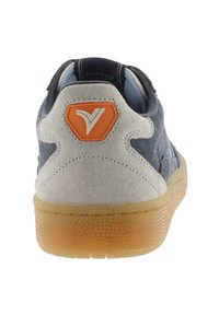 Sneaker blu in suede con tallone beige testurizzato, patch arancione con logo e suola in gomma traslucida. Presenta un collo imbottito per il comfort.