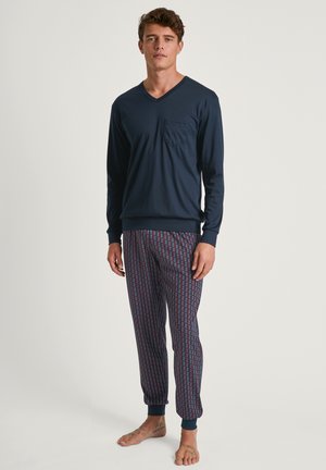 Haut à manches longues V en marine avec poche ; pantalon de pyjama à motifs en bleu et bordeaux avec des chevilles resserrées. Tissu en mélange de coton doux.