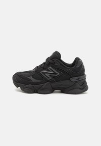Chaussure de sport noire en maille et matériaux synthétiques. Dotée d'une semelle épaisse, d'un col rembourré et d'accents réfléchissants pour la visibilité.