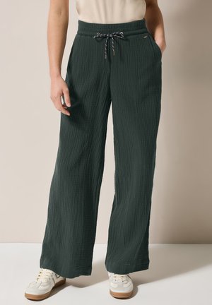 Dunkelgrüne weitgeschnittene Hose aus strukturiertem Stoff, mit einem elastischen Bund und Kordelzug sowie Seitentaschen.