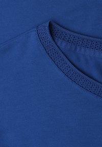 Gros plan d'un tissu tricoté bleu avec un col côtelé texturé et détaillé sur un vêtement.