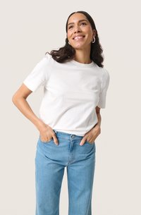 Witte katoenen t-shirt met korte mouwen en een ronde halslijn, gecombineerd met lichtblauwe spijkerbroek. Gladde textuur, relaxte pasvorm.