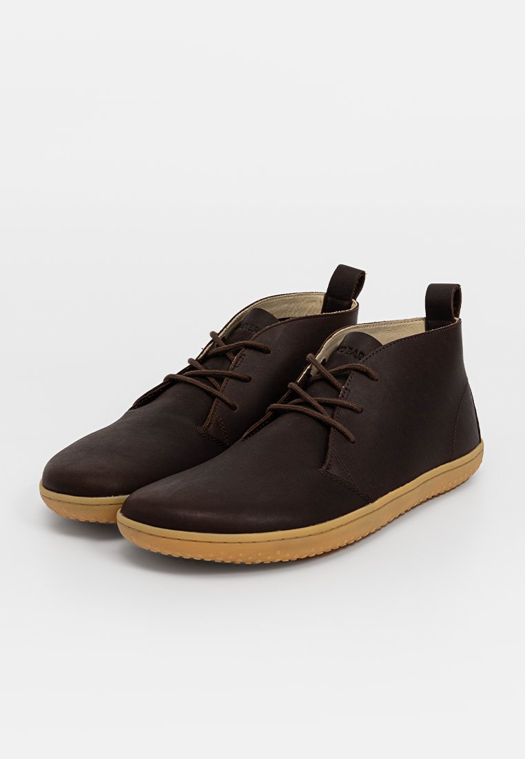 Bottines en cuir marron avec une finition lisse, un design à lacets et une semelle en caoutchouc beige, dotées de rabats latéraux pour un enfilage facile.