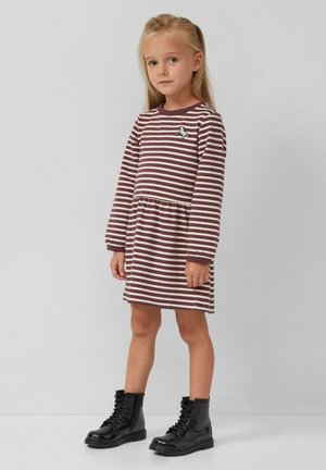 Gestreepte jurk in bruin en crème, met lange mouwen, een getailleerde pasvorm en een speelse eenhoornpatch op de borst. Gecombineerd met zwarte combatlaarzen.