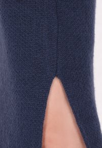 Donkerblauwe trui van een textuur gebreide stof. Heeft een zijsplit detail dat een modern ontwerp benadrukt met een nette afwerking.
