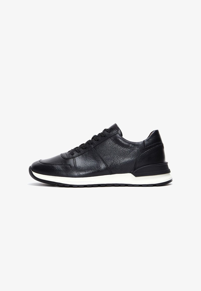 Baskets en cuir noir avec surface texturée, devant à lacets, semelle intermédiaire blanche et semelle extérieure en caoutchouc noir, présentées en profil latéral sur fond blanc.