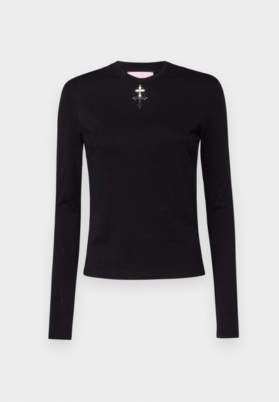 Black long-sleeve top made of smooth fabric, featuring a round neckline and a central silver embellishment with intricate design.