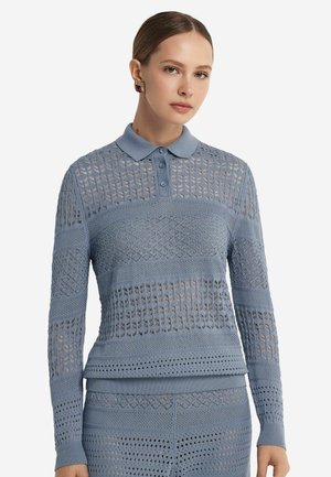 Polo a maniche lunghe di colore blu chiaro, lavorato a maglia, con motivo a traforo, tre bottoni, colletto e polsini a coste. Sezioni testurizzate creano un contrasto visivo.