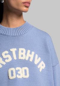 Maglione azzurro chiaro lavorato a maglia con scollatura a costine e lettering fuzzy color crema che recita "RSTBHV" e "030" sul davanti.