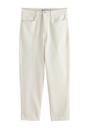 Nærbillede af en person iført cremefarvede jeans og en hvid top med sennepsgule polkaprikker, der viser detaljer ved talje og lommer.
