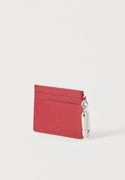 Porte-cartes en cuir rouge avec deux emplacements pour cartes et un porte-clés en métal argenté attaché sur le côté droit, présenté sur fond blanc.