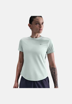 Persona atlética con el cabello peinado hacia atrás, vistiendo una camiseta de manga corta gris claro de Nike y pantalones cortos oscuros, mostrando un antebrazo tatuado.