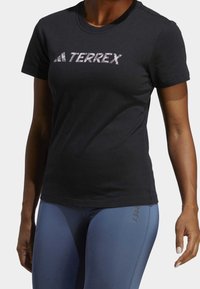Czarna bawełniana koszulka z krótkim rękawem z logo "TERREX" w białym kolorze z przodu, okrągły dekolt. Dopasowany fason o gładkiej teksturze.