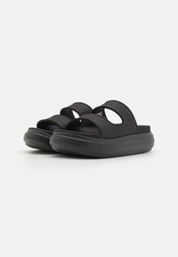 Svarte slidesandaler med to brede stropper, polstret såle og en tykk, strukturert såle for komfort. Minimalistisk design uten dekorasjoner.