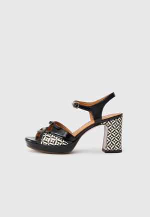 Sandale à talon haut en cuir verni noir avec bride à la cheville, dotée d'un talon bloc à motif géométrique et d'une ouverture à l'avant.