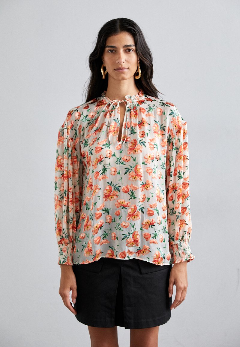 Blusa floral de tejido ligero con flores naranjas y rosas sobre un fondo beige, con escote fruncido y mangas largas elásticas.