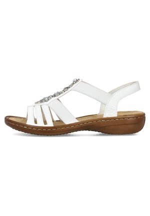 Sandales blanches à bout ouvert, avec des sangles élastiques et des accents décoratifs en perles. La semelle brune, rembourrée, offre confort et stabilité.