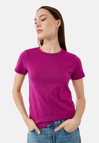 Figurbetontes T-Shirt mit kurzen Ärmeln in leuchtendem Magenta, aus weichem Baumwollstoff, mit Rundhalsausschnitt und minimalen Nähdetails.