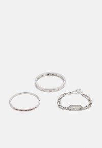 Three metallic bracelets: one slim silver with pink stones, one wider with alternating clear and pink stones, and a chunky chain bracelet with a logo.