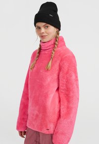 Roze fleece turtleneck sweatshirt met een zachte textuur, een comfortabele pasvorm en lange mouwen. Gecombineerd met een zwarte gebreide beanie.