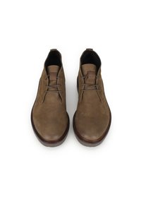 Botas de cuero marrón hasta el tobillo con una textura suave, punta redonda y cuatro ojales para los cordones. Suela de goma con un tacón bajo y detalles de costura.