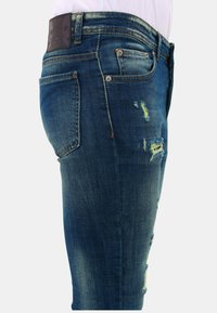 Denim jeans in mediumblauw, met een nauwsluitende pasvorm, versleten details, een leren patch bij de taille en meerdere zakken.