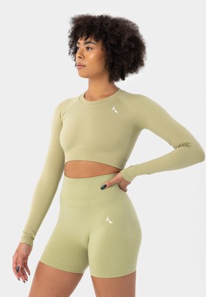 Zestaw sportowy w jasnozielonym kolorze, składający się z długiego crop topu z długim rękawem oraz szortów z wysokim stanem, o prążkowanej fakturze i subtelnych akcentach z logo.