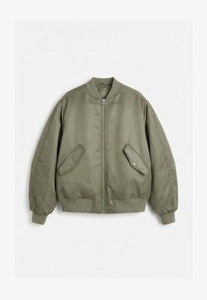 Bomber jakna olivno zelene barve z rebrastim ovratnikom, manšetami in spodnjim robom, sprednjim zadrgo in dvema diagonalnima žepoma s pokrovom in sponkami na pritrditev.