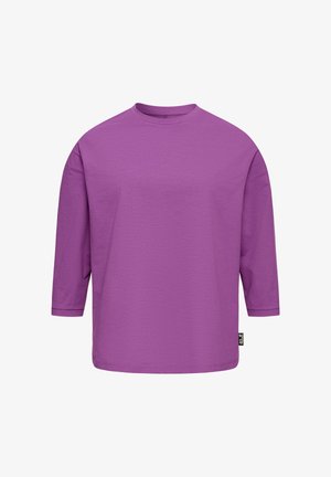 Paarse shirt met lange mouwen en een ronde hals, losvallende pasvorm en een klein zwart label aan de onderzijnaad, tegen een witte achtergrond.