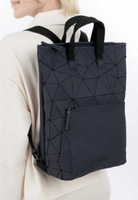 Juodas kuprinė su geometriniu raštu, su nuimamomis petnešomis, viršutine rankena ir priekinis užtrauktuku užsegamas kišenė. Pagaminta iš tvirto medžiagos.