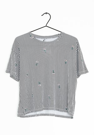 Camicetta a maniche corte a righe in bianco e nero, con dettagli in ricamo floreale. Tessuto leggero, scollatura rotonda e un design dalla vestibilità rilassata.
