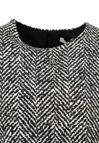 Collo in tessuto di lana a zigzag bianco e nero con una spilla metallica con logo DG sul petto, che mostra parte della fodera interna nera.