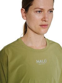 Kobieta o jasnej karnacji i zielonych oczach, ubrana w jasnoniebieski t-shirt HALO, zwrócona lekko w prawo na białym tle.