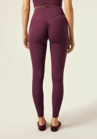 Burgundy leggings med hög midja, med en rynkad detalj bak och ett mjukt, elastiskt tyg.