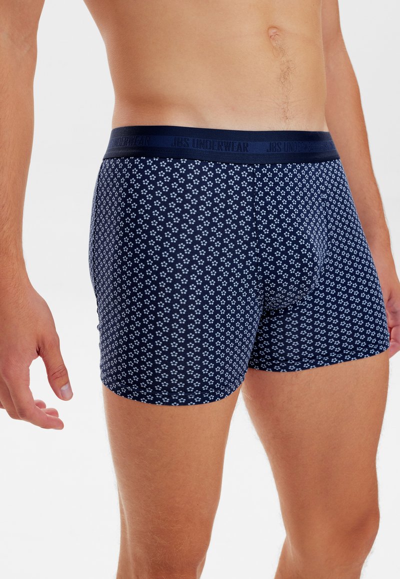 Navy blue boxer shorts with a small white floral pattern, featuring a contrasting waistband labeled "JBS UNDERWEAR." Soft, stretchy fabric.