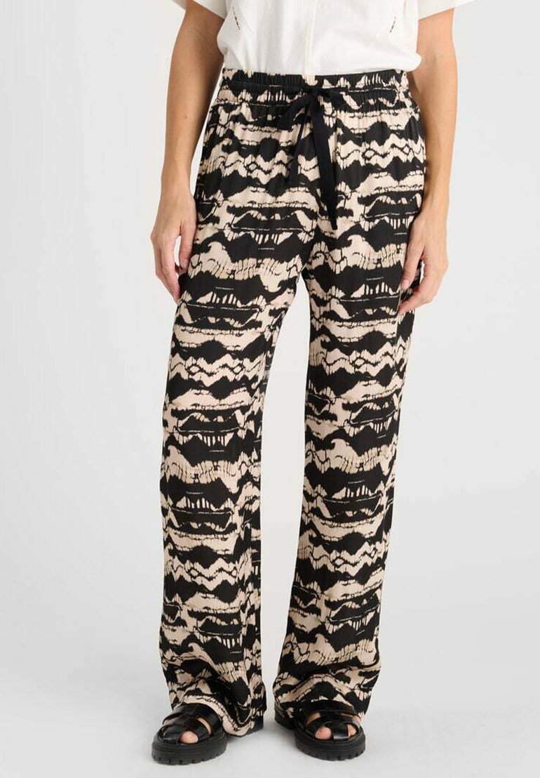 Pantalons larges noirs et beiges à motifs, avec une taille élastique, un système de fermeture à cordon et une coupe décontractée. Le matériau semble léger et doux.