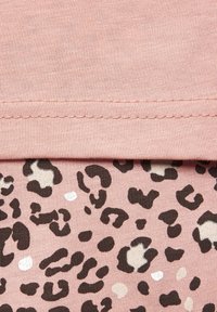Pink fabric with a textured surface and seam at the top; beneath, a patterned section featuring black and cream leopard spots on a light pink background.