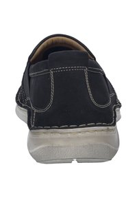 Czarne buty casualowe o gładkiej fakturze, z kontrastującymi białymi szwami i zaokrąglonym noskiem. Posiadają wyściełany kołnierz i gumową podeszwę.