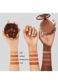 Bronze Goddess Bronzer in einem Kompaktgehäuse mit Schildpatt-Design; zeigt Farbmuster auf Armen mit vier Nuancen: Hell, Mittel, Mittel-Dunkel, Dunkel.