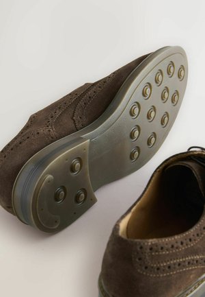 Kavos zomšos oksfordo bateliai su apvalia nosimi, perforuotu dizainu ir guminiu padu su apvalių raštų protektoriumi.