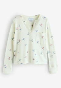 Langärmeliges, cremefarbenes Oberteil aus strukturiertem Waffelstrick, mit V-Ausschnitt und einer aufgesetzten Tasche vorn, die ein verspieltes Ski-Muster in verschiedenen Farben zeigt.