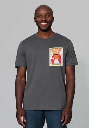 Grijze katoenen t-shirt met een kleurrijke grafische print van handen die een kom vasthouden, met daarboven een luchtballon. Korte mouwen en ronde hals.