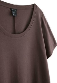 Brun kortærmet T-shirt lavet af blødt stof, med rund halsudskæring og pæne syninger, samt et hængende mærke med størrelseinformation.