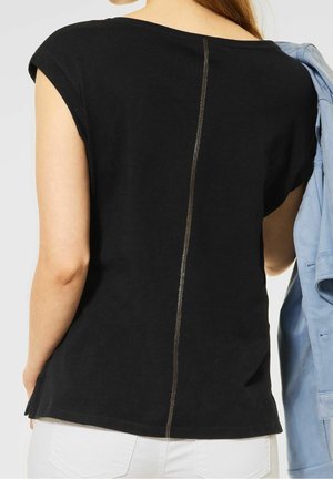 Czarny bawełniany top z krótkim rękawem z centralnym metalowym suwakiem biegnącym pionowo wzdłuż pleców, w luźnym kroju i okrągłym dekoltem.